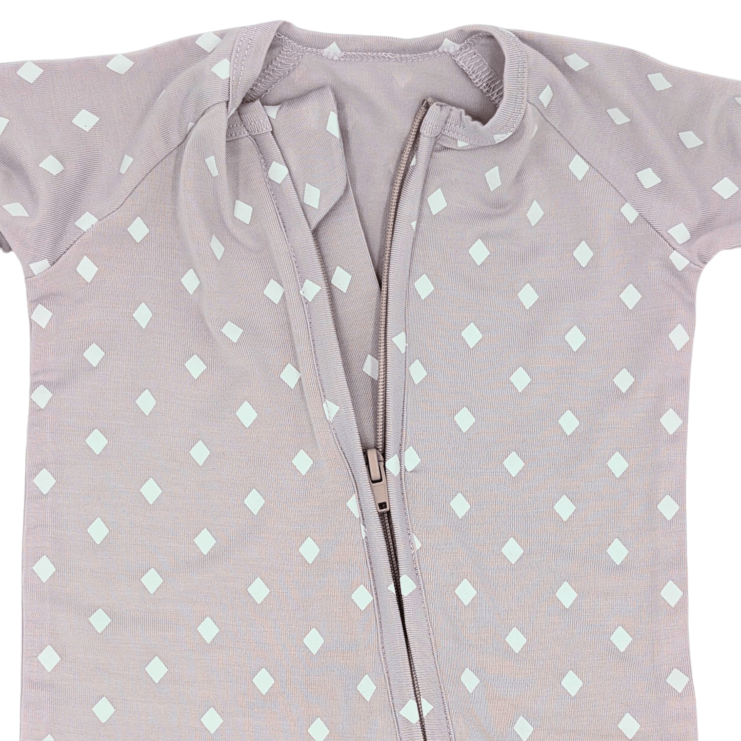 Dettaglio della cerniera della tutina in bambù lilla a pois, progettata per cambi rapidi e senza stress per il neonato.