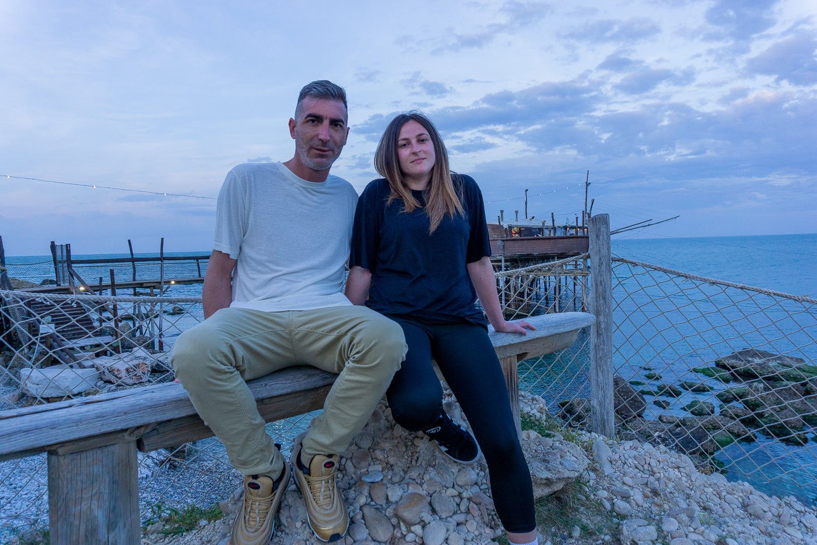 Coppia seduta con abiti sostenibili in bambù e canapa, vista mare - moda naturale e confortevole EcoZone